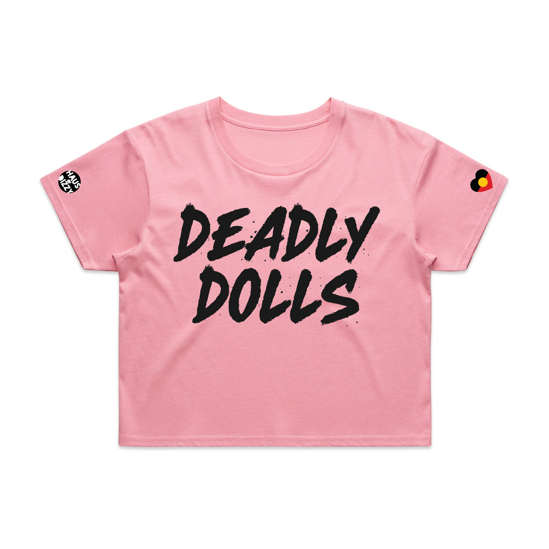 image of haus of dizzy baby pink short-sleeve crop top t-shirt featuring the words 'DEADLY DOLLS' printed in a bold black brush-stroke font across the chest. haus of dizzy logo decal on right sleeve and aboriginal heart flag decal on left sleeve.