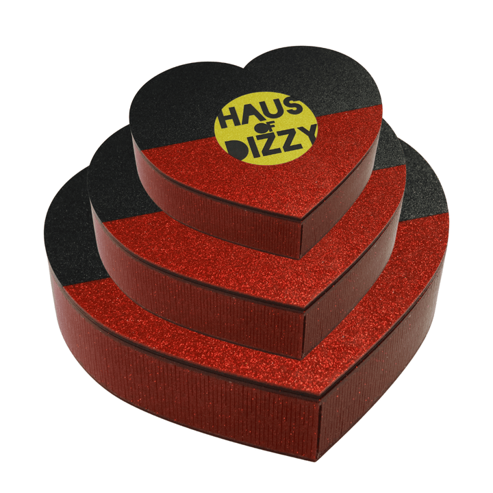 image of all three sizes stacked on top of eachother of our hand made heart-shaped acrylic jewellery box in Aboriginal flag colours. using black, yellow, and red glitter acrylic with hand painted haus of dizzy logo in yellow sun centre