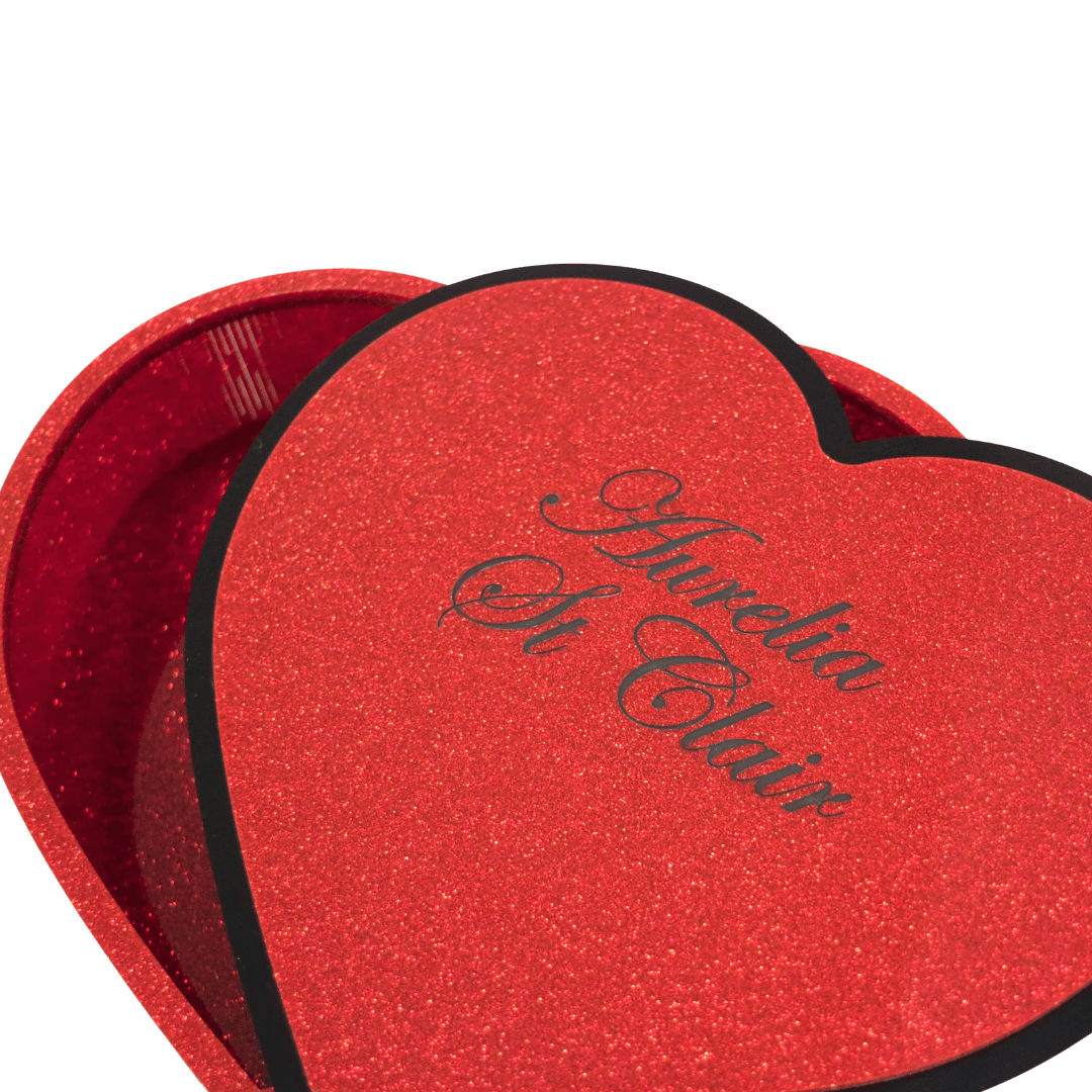 hand made heart-shaped acrylic jewellery box in Aboriginal flag colours. box lid is upside down revealing custom engraving which is an additional $10, black cursive font reads aurelia st clair close up