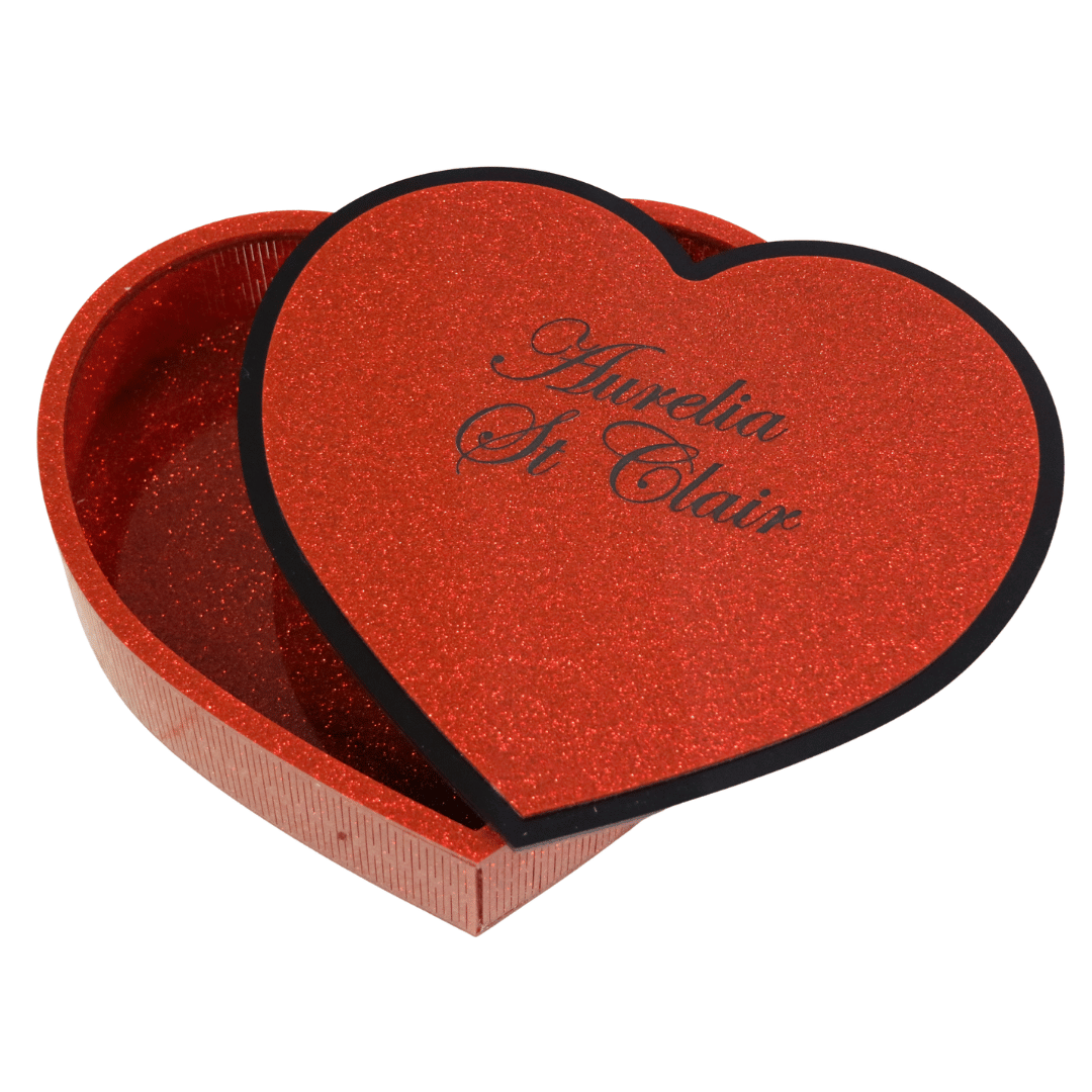 hand made heart-shaped acrylic jewellery box in Aboriginal flag colours. box lid is upside down revealing custom engraving which is an additional $10, black cursive font reads aurelia st clair