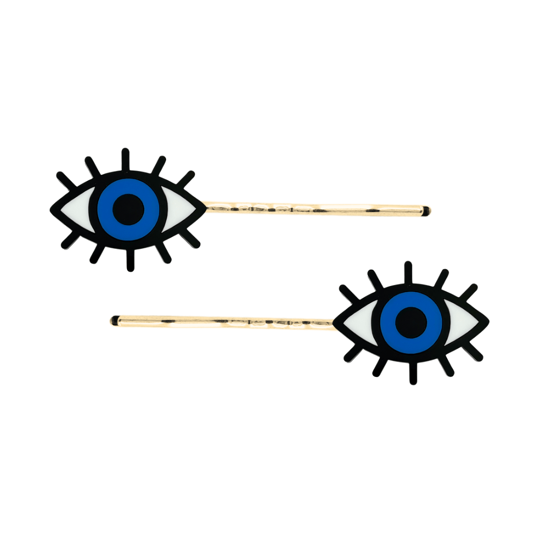 haus of dizzy eye see you hair pins set of two. Eye-shaped hair pins with blue centers and gold hairpins on a white background