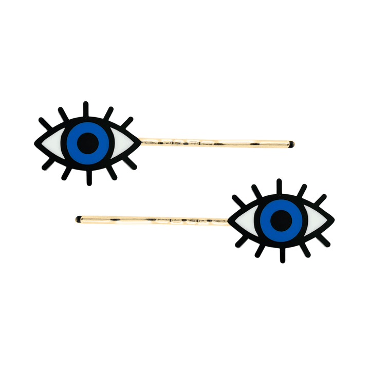 haus of dizzy eye see you hair pins set of two. Eye-shaped hair pins with blue centers and gold hairpins on a white background