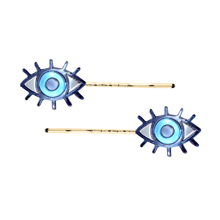 haus of dizzy eye see you hair pins set of two. Eye-shaped hair pins with blue mirror centers and gold hairpins on a white background