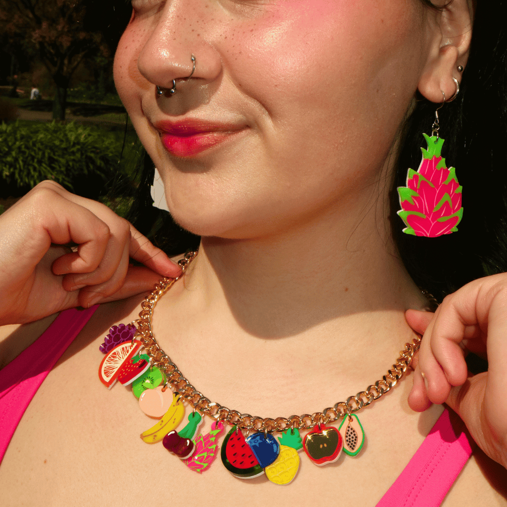 close up shot of model wearing haus of dizzy's fruit salad charm necklace with gold chain and assorted coloured fruits.