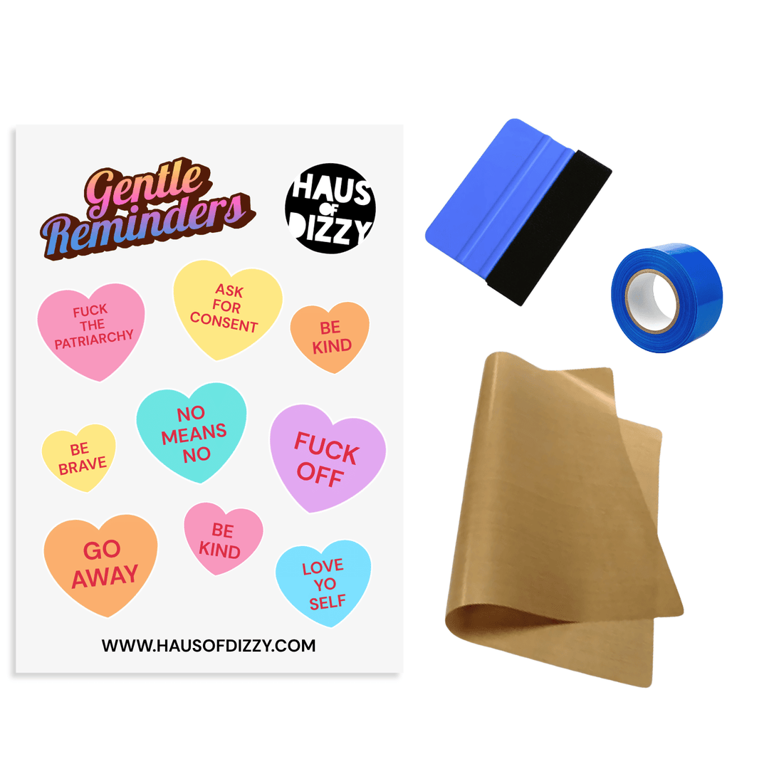DIY Iron-On Transfer Kit by Haus of Dizzy, featuring a sheet of various gentle reminder candy heart decals, a squeegee, blue heat-proof tape, and brown teflon paper included.