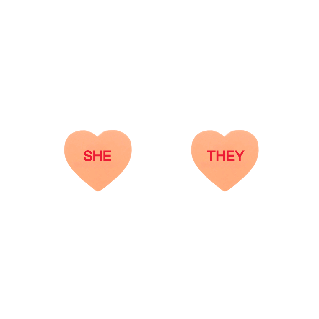 haus of dizzy pastel peach candy heart studs with pronouns SHE and THEY in hand painted red text one word on each stud