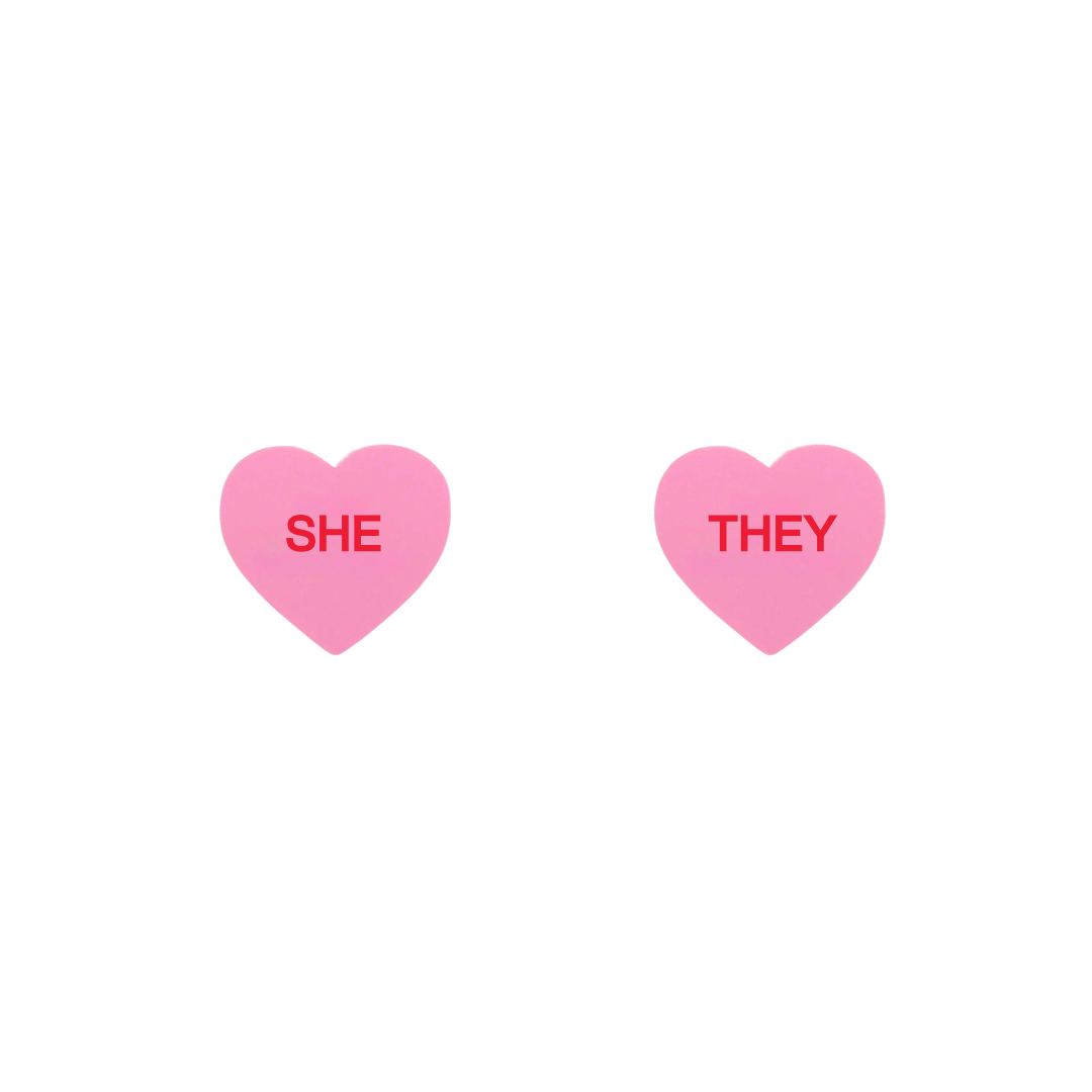 haus of dizzy pastel pink candy heart studs with pronouns SHE and THEY in hand painted red text one word on each stud