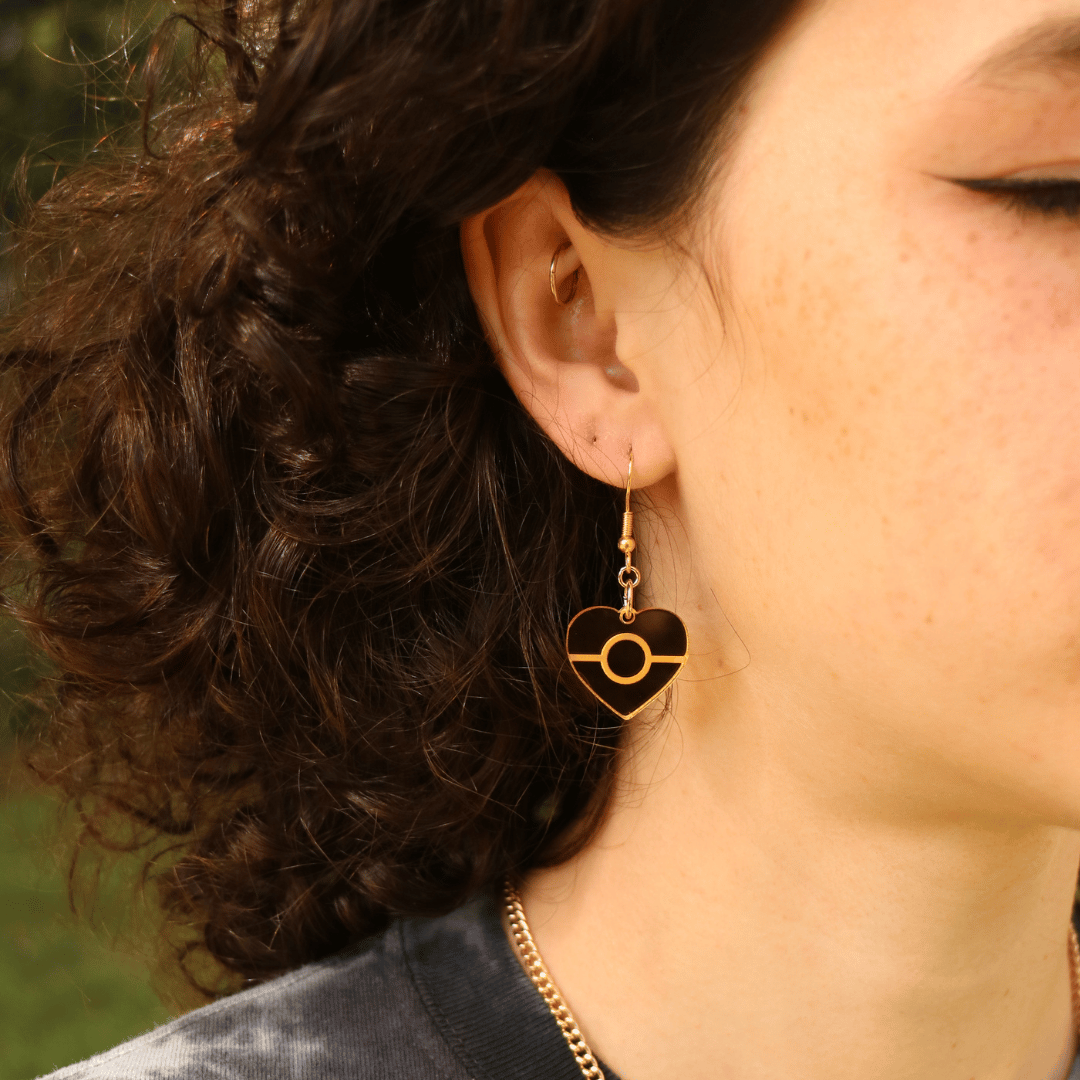 close up of model wearing haus of dizzy mini mirror aboriginal flag heart earring in gold mirror 