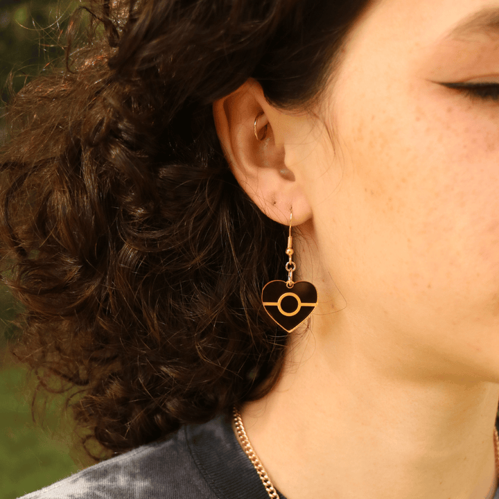 close up of model wearing haus of dizzy mini mirror aboriginal flag heart earring in gold mirror 