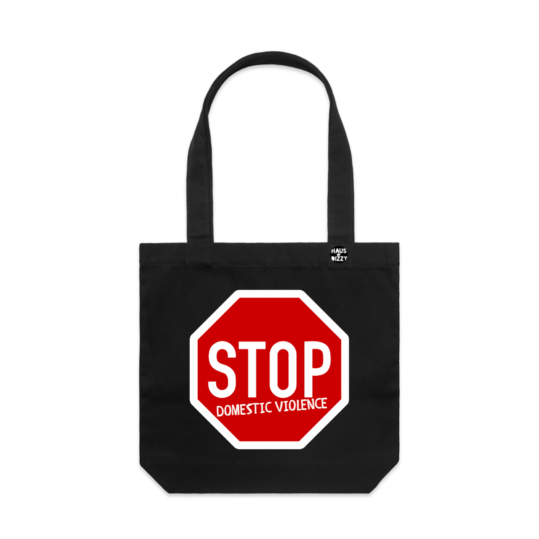 haus of dizzys black canvas tote bag with a red and white stop sign graphic on the front that reads 'STOP DOMESTIC VIOLENCE'. The bag has two black shoulder straps and a small white printed logo on the upper right side.