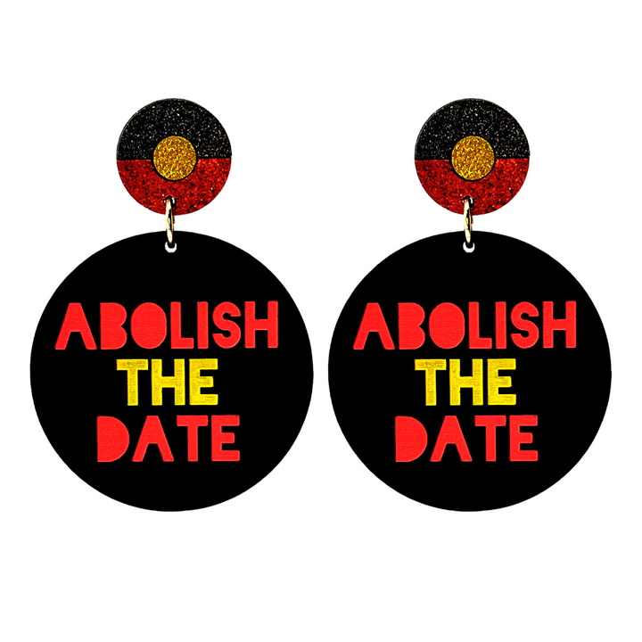 A pair of earrings with a black background, featuring a red, yellow, and black Aboriginal flag circle top with the text 'ABOLISH THE DATE' in bold colors.