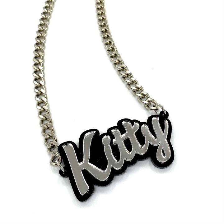haus of dizzy custom name necklace. black background with silver mirror text that reads kitty on silver chain